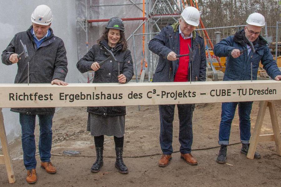 Symbolische Zimmermannsnägel werden zum Richtfest des Carbonbetonhauses in einen Balken geschlagen. (Foto: Stefan Gröschel, IMB, TU Dresden)