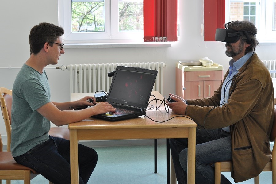 Zwei Männer testen eine VR-Reha-App.