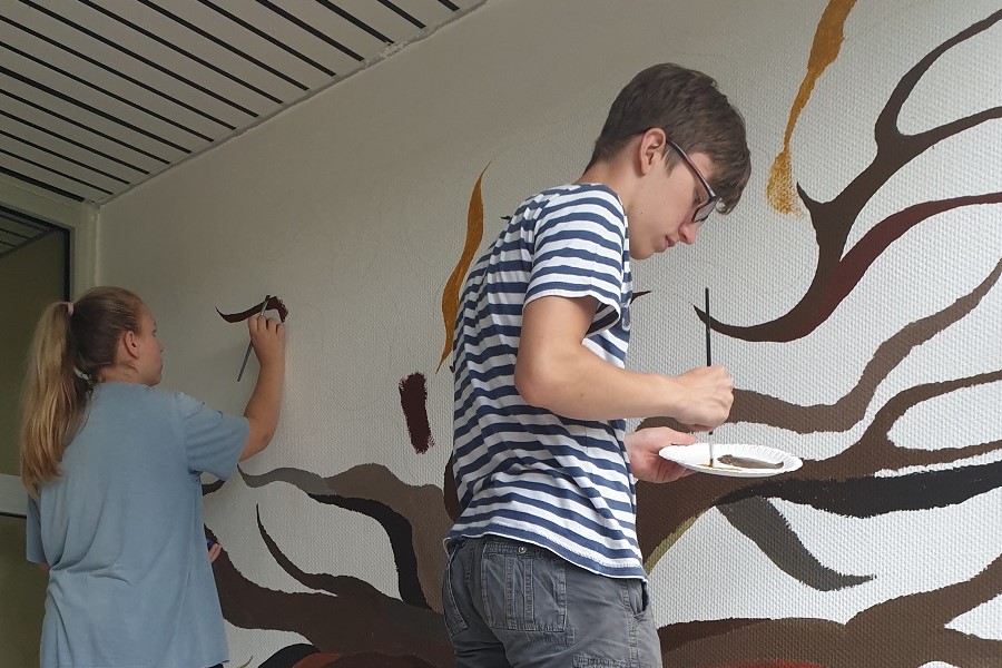 Kinder malen einen Baum an die Wand.
